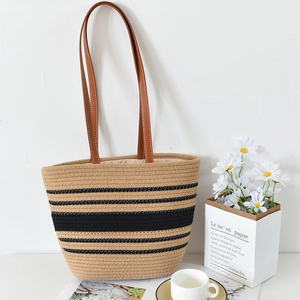 Detailed close-up of woven tote bag featuring black stripes and brown leather straps