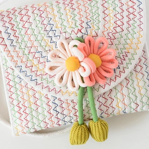 Detail der handgewebten Umhängetasche mit bunten Zickzacknähten und 3D-Blumenapplikationen