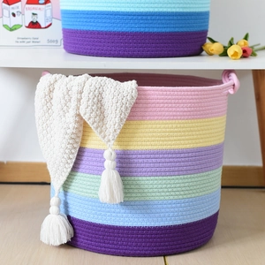 Dettaglio del cesto in corda di cotone arcobaleno con doppi manici e nappe bianche