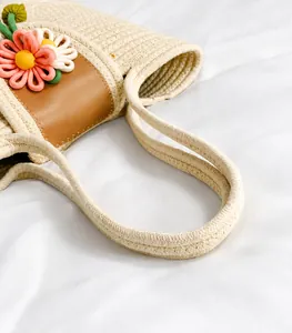 Close-up of comfortable thick rope handles and knit flower detail on beige woven bag