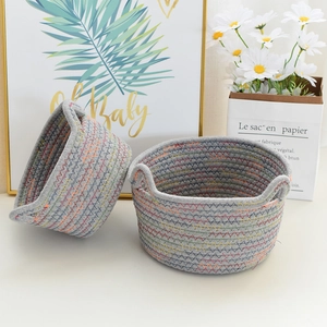 Detail of grey woven cotton rope storage baskets with colorful stitching and side handles