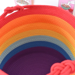 Dettaglio del cesto in corda di cotone arcobaleno con focus sulla maniglia intrecciata