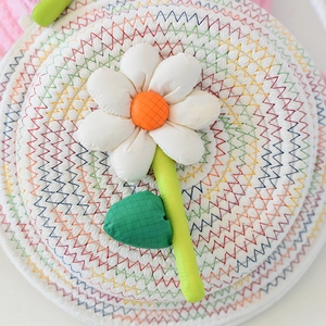 Détail du sac fourre-tout tissé avec une grande fleur de soleil 3D et des coutures colorées