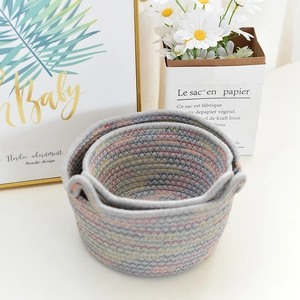 Detailed close-up of nesting grey woven cotton storage baskets with colorful wavy stitching
