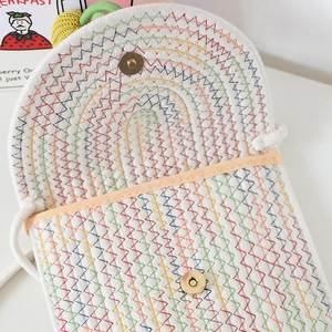 Nahaufnahme der geflochtenen Tasche mit Regenbogennaht und goldenen Magnetknöpfen