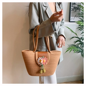 Detail of hand-woven straw tote bag with brown leather flap and 3D floral accents