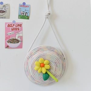 Détail du sac tissé rond avec coutures arc-en-ciel et fleur jaune en peluche