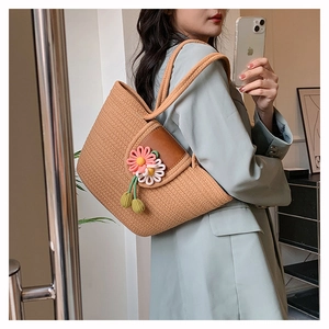 Detailed close-up of woven tote bag with 3D floral accents on a female model