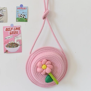 Détail d'un sac bandoulière rose tissé circulaire avec fleur en tissu 3D et texture en coton