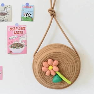 Détail d'un sac bandoulière rond en paille pour enfant avec fleur décorative