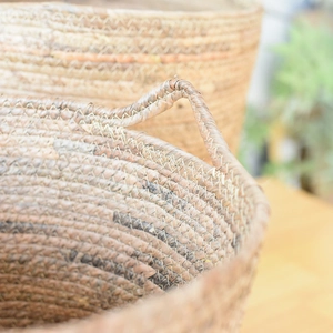 Macro view of woven plant fiber basket with bicolor spiral pattern and sturdy handles