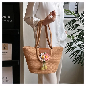 Detail of hand-woven straw tote bag with floral decorations in a lifestyle setting