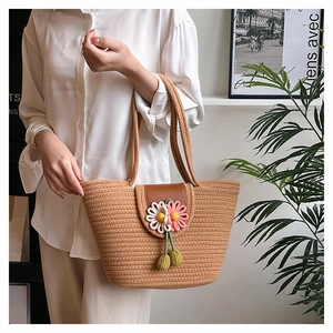 Detailed close-up of handmade straw tote bag with woven flowers and leather flap closure
