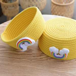 Close-up of bright yellow cotton rope storage baskets with rainbow patch on wood desk