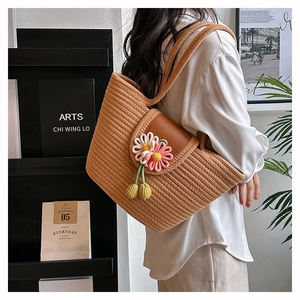 Detail of hand-woven straw tote with 3D knitted daisies and vibrant tassel charms
