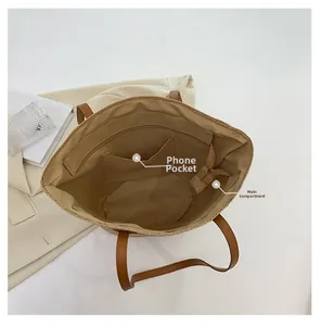 Détail du sac cabas en paille montrant les compartiments intérieurs et la poche