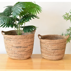 Handwoven seagrass plant baskets set with handles and greenery for home decor