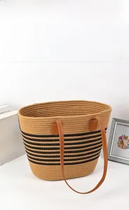 Close-up of woven tote bag texture with horizontal black stripes and leather handles