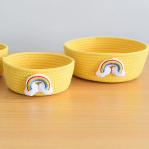 Detail of yellow cotton rope storage basket with rainbow embroidery and soft cloud motif