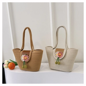 Detail of woven straw tote bags in beige and khaki with leather flap and daisy charm