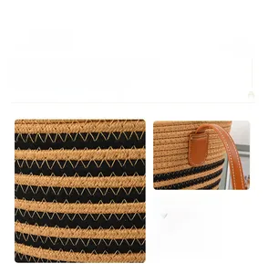 Close-up of striped woven tote bag featuring brown leather handles and white stitching details