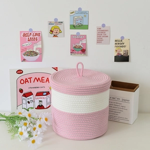 Dettaglio del cesto portaoggetti in cotone intrecciato rosa e bianco con coperchio e maniglia
