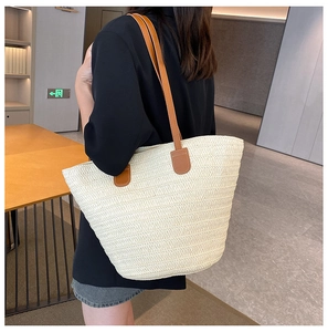 Détail d'un grand sac cabas en paille avec bandoulières en cuir marron et texture tissée