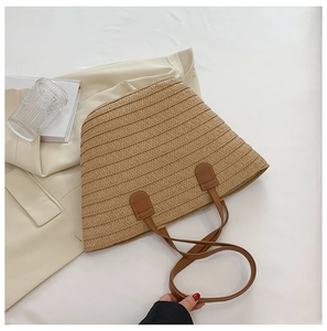 Vue à plat d'un sac cabas en paille tissée avec poignées en similicuir marron d'été