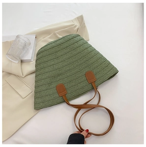 Détail du sac cabas en paille verte avec anses en cuir marron et fermeture éclair