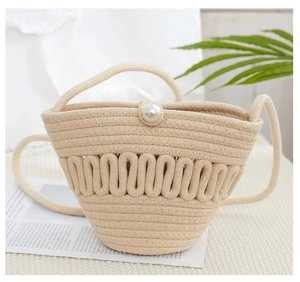 Detail of woven straw bucket bag featuring a large pearl clasp and wavy texture
