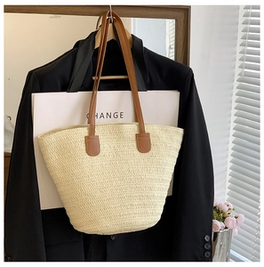 Gros plan du sac cabas en paille tissée avec anses en cuir marron et texture détaillée