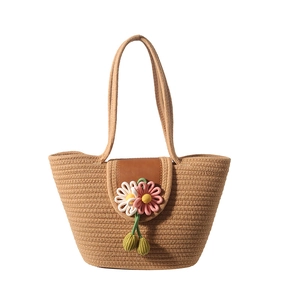 Handwoven khaki straw tote bag with brown leather flap and crochet flower charms