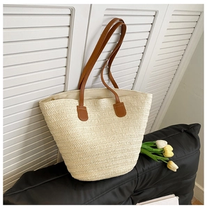 Gros plan du sac cabas en paille beige avec fines lanières en cuir marron