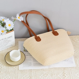 Minimalist straw woven tote bag with brown leather handles for summer beach vacation