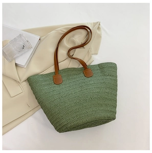 Détail du cabas en paille tissé vert herbe avec bandoulières en cuir marron pour vacances