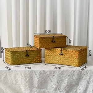 Detailed view of three sizes of rectangular seagrass storage baskets with lids and toggles