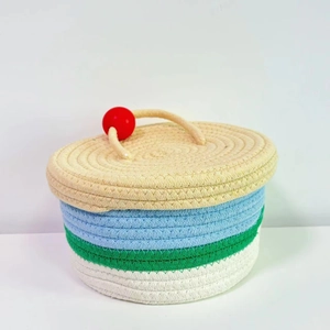 Close-up of handmade cotton rope storage basket with red ball handle and tricolor layers