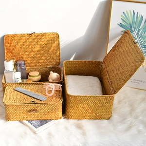 Macro detail of three-piece natural seagrass woven storage baskets with lids and toggles