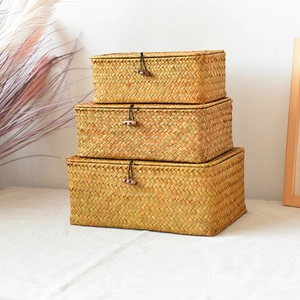 Macro shot of three stacked woven seagrass storage boxes with wood toggle closures