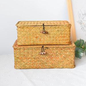 Detail of stacked rectangular seagrass storage boxes with wooden toggles and elastic closures