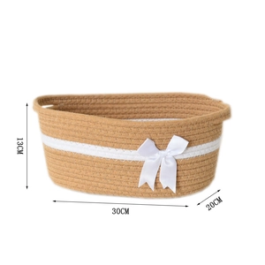 Detailed view of woven cotton rope storage basket with white stripes and satin bow