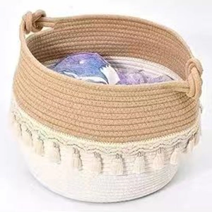 Detail of woven cotton rope storage basket featuring bicolor design and tassel fringe accents