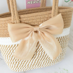 Detail of woven straw handbag with a large champagne satin bow and striped texture