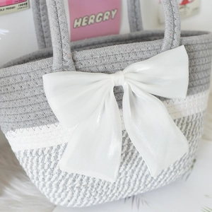 Detail of grey and white woven cotton handbag featuring a large glossy satin bow decoration