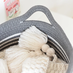 Close-up of woven cotton rope basket with handle showing texture and fringe detail
