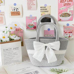 Detail of hand-woven cotton striped handbag with white satin bow and ring handles