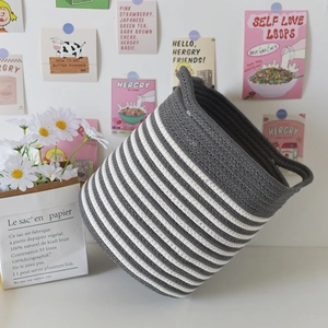 Close-up detail of grey and white striped woven cotton rope storage basket with handles