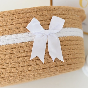 Close-up of hand-woven cotton rope storage basket featuring a white satin bow detail