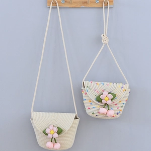 Détail de sacs à bandoulière tressés à la main avec fleurs roses et cerises pour enfants