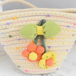 Detailed close-up of handmade woven straw bag with colorful tassels and knit bow